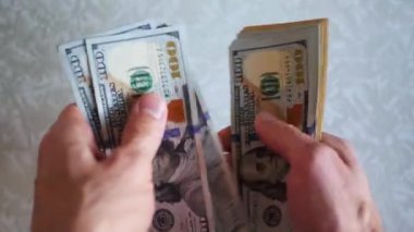 Bir yığın gevrek, dolar banknotları, becerikli ellerde tutuluyor. Adam kağıt para sayıyor. Bir Amerikan para akışı. Bir sürü Amerikan doları. ABD banknotlarının yakın plan görüntüsü. İşadamı elindeki banknotları sayar. Elinde parası olan adam..