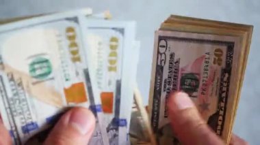 Bir yığın gevrek, dolar banknotları, becerikli ellerde tutuluyor. Adam kağıt para sayıyor. Bir Amerikan para akışı. Bir sürü Amerikan doları. ABD banknotlarının yakın plan görüntüsü. İşadamı elindeki banknotları sayar. Elinde parası olan adam..