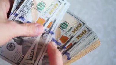 Bir yığın gevrek, dolar banknotları, becerikli ellerde tutuluyor. Adam kağıt para sayıyor. Bir Amerikan para akışı. Bir sürü Amerikan doları. ABD banknotlarının yakın plan görüntüsü. İşadamı elindeki banknotları sayar. Elinde parası olan adam..