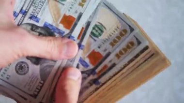 Bir yığın gevrek, dolar banknotları, becerikli ellerde tutuluyor. Adam kağıt para sayıyor. Bir Amerikan para akışı. Bir sürü Amerikan doları. ABD banknotlarının yakın plan görüntüsü. İşadamı elindeki banknotları sayar. Elinde parası olan adam..