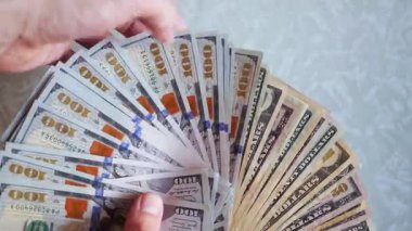 Bir yığın gevrek, dolar banknotları, becerikli ellerde tutuluyor. Adam kağıt para sayıyor. Bir Amerikan para akışı. Bir sürü Amerikan doları. ABD banknotlarının yakın plan görüntüsü. İşadamı elindeki banknotları sayar. Elinde parası olan adam..