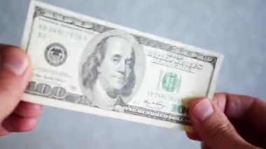 Bir yığın gevrek, dolar banknotları, becerikli ellerde tutuluyor. Adam kağıt para sayıyor. Bir Amerikan para akışı. Bir sürü Amerikan doları. ABD banknotlarının yakın plan görüntüsü. İşadamı elindeki banknotları sayar. Elinde parası olan adam..