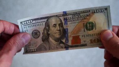 Bir yığın gevrek, dolar banknotları, becerikli ellerde tutuluyor. Adam kağıt para sayıyor. Bir Amerikan para akışı. Bir sürü Amerikan doları. ABD banknotlarının yakın plan görüntüsü. İşadamı elindeki banknotları sayar. Elinde parası olan adam..
