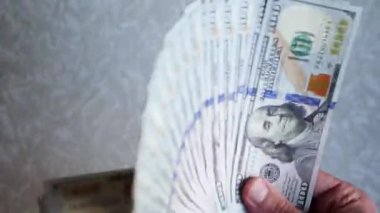 Bir yığın gevrek, dolar banknotları, becerikli ellerde tutuluyor. Adam kağıt para sayıyor. Bir Amerikan para akışı. Bir sürü Amerikan doları. ABD banknotlarının yakın plan görüntüsü. İşadamı elindeki banknotları sayar. Elinde parası olan adam..