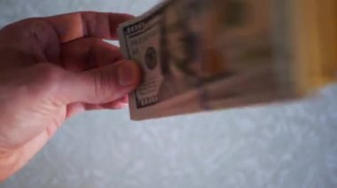 Bir yığın gevrek, dolar banknotları, becerikli ellerde tutuluyor. Adam kağıt para sayıyor. Bir Amerikan para akışı. Bir sürü Amerikan doları. ABD banknotlarının yakın plan görüntüsü. İşadamı elindeki banknotları sayar. Elinde parası olan adam..