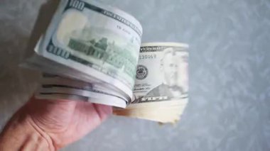 Bir yığın gevrek, dolar banknotları, becerikli ellerde tutuluyor. Adam kağıt para sayıyor. Bir Amerikan para akışı. Bir sürü Amerikan doları. ABD banknotlarının yakın plan görüntüsü. İşadamı elindeki banknotları sayar. Elinde parası olan adam..