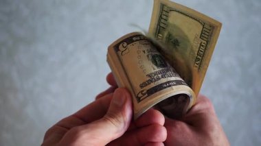 Bir yığın gevrek, dolar banknotları, becerikli ellerde tutuluyor. Adam kağıt para sayıyor. Bir Amerikan para akışı. Bir sürü Amerikan doları. ABD banknotlarının yakın plan görüntüsü. İşadamı elindeki banknotları sayar. Elinde parası olan adam..
