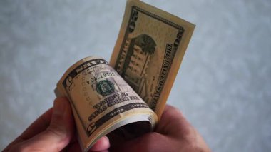 Bir yığın gevrek, dolar banknotları, becerikli ellerde tutuluyor. Adam kağıt para sayıyor. Bir Amerikan para akışı. Bir sürü Amerikan doları. ABD banknotlarının yakın plan görüntüsü. İşadamı elindeki banknotları sayar. Elinde parası olan adam..