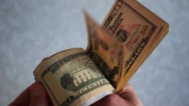 Bir yığın gevrek, dolar banknotları, becerikli ellerde tutuluyor. Adam kağıt para sayıyor. Bir Amerikan para akışı. Bir sürü Amerikan doları. ABD banknotlarının yakın plan görüntüsü. İşadamı elindeki banknotları sayar. Elinde parası olan adam..
