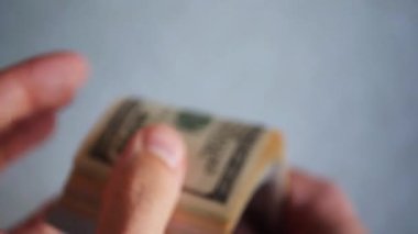 Bir yığın gevrek, dolar banknotları, becerikli ellerde tutuluyor. Adam kağıt para sayıyor. Bir Amerikan para akışı. Bir sürü Amerikan doları. ABD banknotlarının yakın plan görüntüsü. İşadamı elindeki banknotları sayar. Elinde parası olan adam..