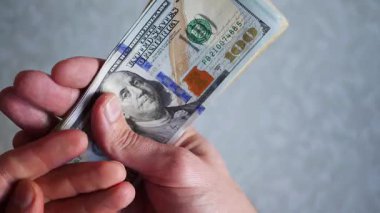 Bir yığın gevrek, dolar banknotları, becerikli ellerde tutuluyor. Adam kağıt para sayıyor. Bir Amerikan para akışı. Bir sürü Amerikan doları. ABD banknotlarının yakın plan görüntüsü. İşadamı elindeki banknotları sayar. Elinde parası olan adam..