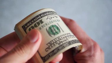 Bir yığın gevrek, dolar banknotları, becerikli ellerde tutuluyor. Adam kağıt para sayıyor. Bir Amerikan para akışı. Bir sürü Amerikan doları. ABD banknotlarının yakın plan görüntüsü. İşadamı elindeki banknotları sayar. Elinde parası olan adam..