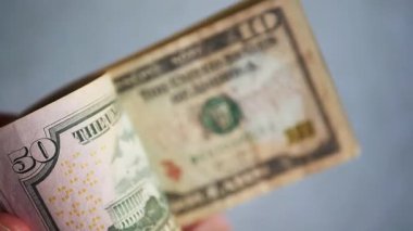 Bir yığın gevrek, dolar banknotları, becerikli ellerde tutuluyor. Adam kağıt para sayıyor. Bir Amerikan para akışı. Bir sürü Amerikan doları. ABD banknotlarının yakın plan görüntüsü. İşadamı elindeki banknotları sayar. Elinde parası olan adam..
