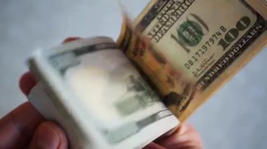 Bir yığın gevrek, dolar banknotları, becerikli ellerde tutuluyor. Adam kağıt para sayıyor. Bir Amerikan para akışı. Bir sürü Amerikan doları. ABD banknotlarının yakın plan görüntüsü. İşadamı elindeki banknotları sayar. Elinde parası olan adam..