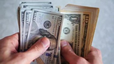 Bir yığın gevrek, dolar banknotları, becerikli ellerde tutuluyor. Adam kağıt para sayıyor. Bir Amerikan para akışı. Bir sürü Amerikan doları. ABD banknotlarının yakın plan görüntüsü. İşadamı elindeki banknotları sayar. Elinde parası olan adam..