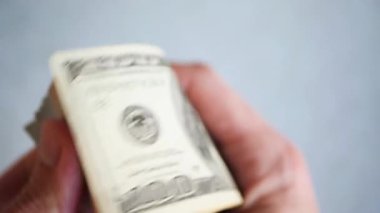 Bir yığın gevrek, dolar banknotları, becerikli ellerde tutuluyor. Adam kağıt para sayıyor. Bir Amerikan para akışı. Bir sürü Amerikan doları. ABD banknotlarının yakın plan görüntüsü. İşadamı elindeki banknotları sayar. Elinde parası olan adam..