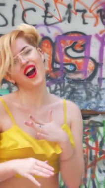 Dikey. Kız kizomba yapıyor. Grafiti arka planında dans eden seksi, komik kadın. Güzel genç dansçı baştan çıkarıcı bir şekilde dans eder ve kalçasını oynatır. Graffiti, kaykay parkı.