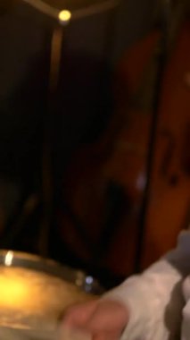 Dikey. Beyaz gömlekli adam stüdyoda davul çalıyor. Müzik grubu restoranda çalar. Gece romantik bir ışıktır. Jazz, Blues, Funk Retro stüdyosu, tuğla iç mekan.