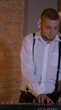 Dikey. Adam stüdyoda sentezleyici çalıyor. Elektrikli piyano. İplerin ve pulların makro çekimi. Müzik grubu restoranda çalar. Gece romantik bir ışıktır. Caz, Blues, Funk Retro
