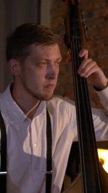 Dikey. Adam stüdyoda bas gitar çalıyor. İplerin ve pulların makro çekimi. Müzik grubu restoranda çalar. Gece romantik bir ışıktır. Caz, Blues, Funk Retro Stüdyosu,