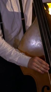 Dikey. Adam stüdyoda bas gitar çalıyor. İplerin ve pulların makro çekimi. Müzik grubu restoranda çalar. Gece romantik bir ışıktır. Caz, Blues, Funk Retro Stüdyosu,