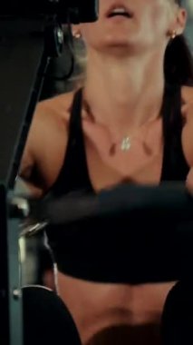 Dikey. Spor salonunda bir kadın, gücü ve hassasiyeti somutlaştırıyor. Ter parlıyor, kaslar çalışıyor. Bir bayan sporcu antrenman yapıyor, limitlerini zorluyor. Güçlü bir atletizm gösterisi. Güzel vücut şekilleri