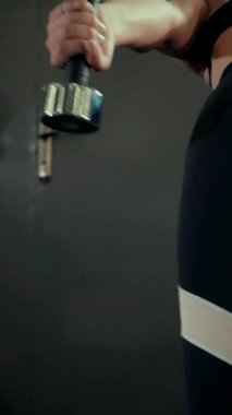 Dikey. Spor salonunda bir kadın, gücü ve hassasiyeti somutlaştırıyor. Ter parlıyor, kaslar çalışıyor. Bir bayan sporcu antrenman yapıyor, limitlerini zorluyor. Güçlü bir atletizm gösterisi. Güzel vücut şekilleri