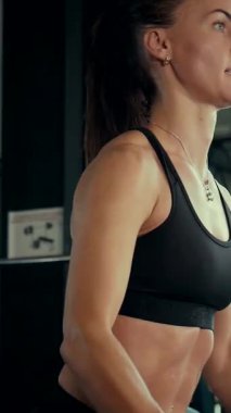 Dikey. Spor salonunda bir kadın, gücü ve hassasiyeti somutlaştırıyor. Ter parlıyor, kaslar çalışıyor. Bir bayan sporcu antrenman yapıyor, limitlerini zorluyor. Güçlü bir atletizm gösterisi. Güzel vücut şekilleri