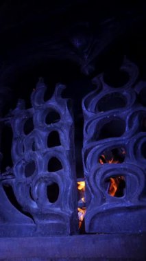 Dikey. Karmaşık, süslü eski şömine, oyulmuş açıklıklarda dans eden alevler. Yangından yayılan sıcaklık, yontulmuş bir şöminenin içinde. Kale şöminesinde şömine, soba..