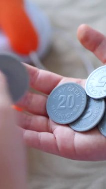 Dikey. Bir çocuğun elleri dikkatli bir şekilde oyun paralarını tutar, çıtır gagalar küçük kanatlar gibi çırpınır. Taklit para birimi, titizlikle sıralanmış, sahte bir satın alma için hazır. Nakit oyun, minyatür bir pazar.