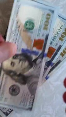 Dikey. Bir yığın gevrek, dolar banknotları, becerikli ellerde tutuluyor. Adam kağıt para sayıyor. Bir Amerikan para akışı. Bir sürü dolar. ABD banknotlarının yakın plan görüntüsü. İşadamı banknotları sayar