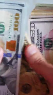 Dikey. Bir yığın gevrek, dolar banknotları, becerikli ellerde tutuluyor. Adam kağıt para sayıyor. Bir Amerikan para akışı. Bir sürü dolar. ABD banknotlarının yakın plan görüntüsü. İşadamı banknotları sayar