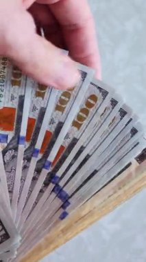 Dikey. Bir yığın gevrek, dolar banknotları, becerikli ellerde tutuluyor. Adam kağıt para sayıyor. Bir Amerikan para akışı. Bir sürü dolar. ABD banknotlarının yakın plan görüntüsü. İşadamı banknotları sayar