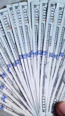 Dikey. Bir yığın gevrek, dolar banknotları, becerikli ellerde tutuluyor. Adam kağıt para sayıyor. Bir Amerikan para akışı. Bir sürü dolar. ABD banknotlarının yakın plan görüntüsü. İşadamı banknotları sayar