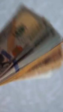 Dikey. Bir yığın gevrek, dolar banknotları, becerikli ellerde tutuluyor. Adam kağıt para sayıyor. Bir Amerikan para akışı. Bir sürü dolar. ABD banknotlarının yakın plan görüntüsü. İşadamı banknotları sayar
