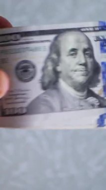 Dikey. Bir yığın gevrek, dolar banknotları, becerikli ellerde tutuluyor. Adam kağıt para sayıyor. Bir Amerikan para akışı. Bir sürü dolar. ABD banknotlarının yakın plan görüntüsü. İşadamı banknotları sayar