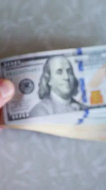 Dikey. Bir yığın gevrek, dolar banknotları, becerikli ellerde tutuluyor. Adam kağıt para sayıyor. Bir Amerikan para akışı. Bir sürü dolar. ABD banknotlarının yakın plan görüntüsü. İşadamı banknotları sayar