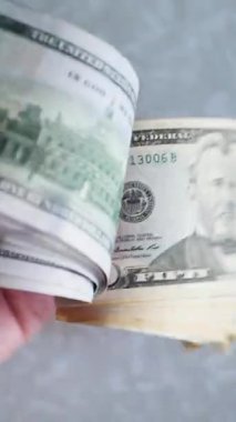 Dikey. Bir yığın gevrek, dolar banknotları, becerikli ellerde tutuluyor. Adam kağıt para sayıyor. Bir Amerikan para akışı. Bir sürü dolar. ABD banknotlarının yakın plan görüntüsü. İşadamı banknotları sayar