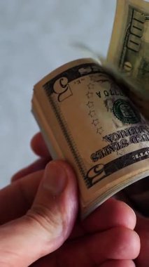 Dikey. Bir yığın gevrek, dolar banknotları, becerikli ellerde tutuluyor. Adam kağıt para sayıyor. Bir Amerikan para akışı. Bir sürü dolar. ABD banknotlarının yakın plan görüntüsü. İşadamı banknotları sayar