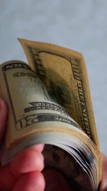 Dikey. Bir yığın gevrek, dolar banknotları, becerikli ellerde tutuluyor. Adam kağıt para sayıyor. Bir Amerikan para akışı. Bir sürü dolar. ABD banknotlarının yakın plan görüntüsü. İşadamı banknotları sayar