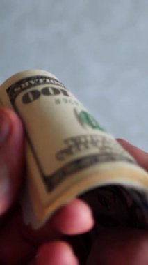 Dikey. Bir yığın gevrek, dolar banknotları, becerikli ellerde tutuluyor. Adam kağıt para sayıyor. Bir Amerikan para akışı. Bir sürü dolar. ABD banknotlarının yakın plan görüntüsü. İşadamı banknotları sayar
