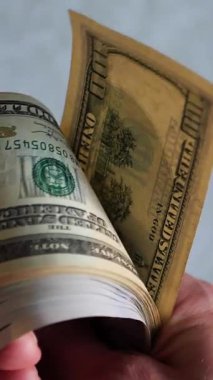 Dikey. Bir yığın gevrek, dolar banknotları, becerikli ellerde tutuluyor. Adam kağıt para sayıyor. Bir Amerikan para akışı. Bir sürü dolar. ABD banknotlarının yakın plan görüntüsü. İşadamı banknotları sayar