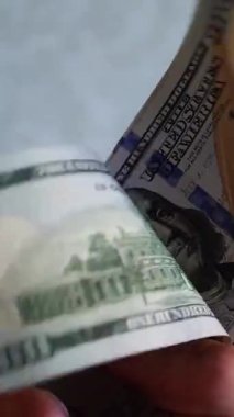 Dikey. Bir yığın gevrek, dolar banknotları, becerikli ellerde tutuluyor. Adam kağıt para sayıyor. Bir Amerikan para akışı. Bir sürü dolar. ABD banknotlarının yakın plan görüntüsü. İşadamı banknotları sayar
