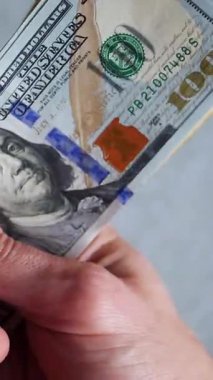 Dikey. Bir yığın gevrek, dolar banknotları, becerikli ellerde tutuluyor. Adam kağıt para sayıyor. Bir Amerikan para akışı. Bir sürü dolar. ABD banknotlarının yakın plan görüntüsü. İşadamı banknotları sayar