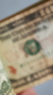 Dikey. Bir yığın gevrek, dolar banknotları, becerikli ellerde tutuluyor. Adam kağıt para sayıyor. Bir Amerikan para akışı. Bir sürü dolar. ABD banknotlarının yakın plan görüntüsü. İşadamı banknotları sayar