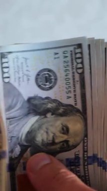 Dikey. Bir yığın gevrek, dolar banknotları, becerikli ellerde tutuluyor. Adam kağıt para sayıyor. Bir Amerikan para akışı. Bir sürü dolar. ABD banknotlarının yakın plan görüntüsü. İşadamı banknotları sayar