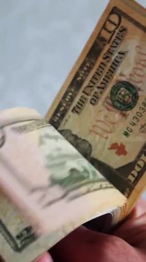 Dikey. Bir yığın gevrek, dolar banknotları, becerikli ellerde tutuluyor. Adam kağıt para sayıyor. Bir Amerikan para akışı. Bir sürü dolar. ABD banknotlarının yakın plan görüntüsü. İşadamı banknotları sayar