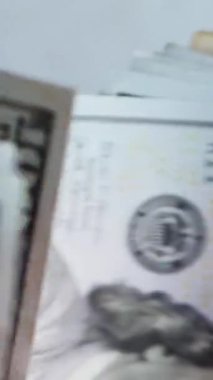 Dikey. Bir yığın gevrek, dolar banknotları, becerikli ellerde tutuluyor. Adam kağıt para sayıyor. Bir Amerikan para akışı. Bir sürü dolar. ABD banknotlarının yakın plan görüntüsü. İşadamı banknotları sayar
