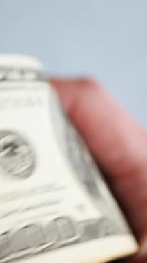 Dikey. Bir yığın gevrek, dolar banknotları, becerikli ellerde tutuluyor. Adam kağıt para sayıyor. Bir Amerikan para akışı. Bir sürü dolar. ABD banknotlarının yakın plan görüntüsü. İşadamı banknotları sayar