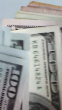Dikey. Bir yığın gevrek, dolar banknotları, becerikli ellerde tutuluyor. Adam kağıt para sayıyor. Bir Amerikan para akışı. Bir sürü dolar. ABD banknotlarının yakın plan görüntüsü. İşadamı banknotları sayar